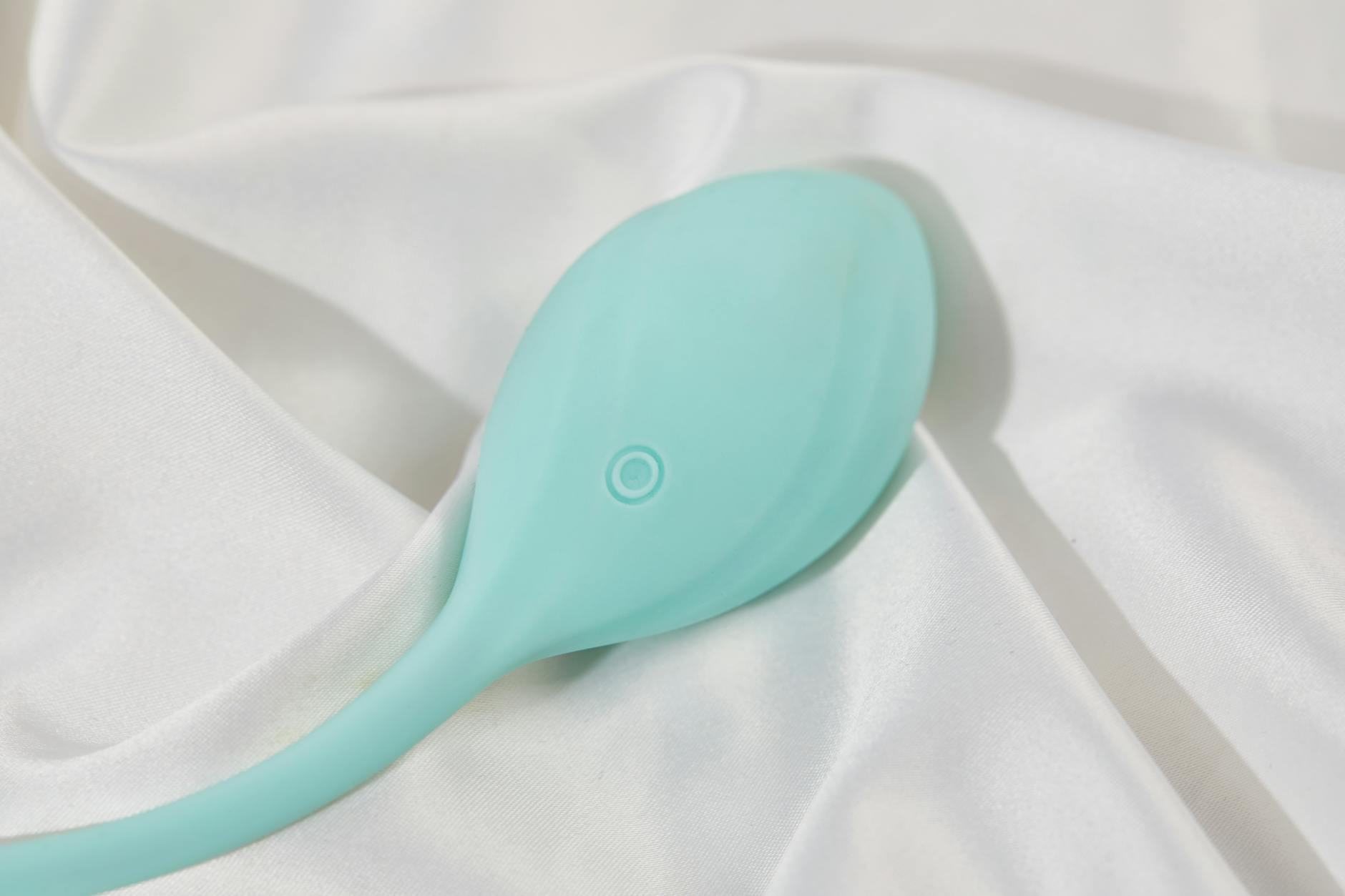 A stylish vibrator on smooth white silk fabric