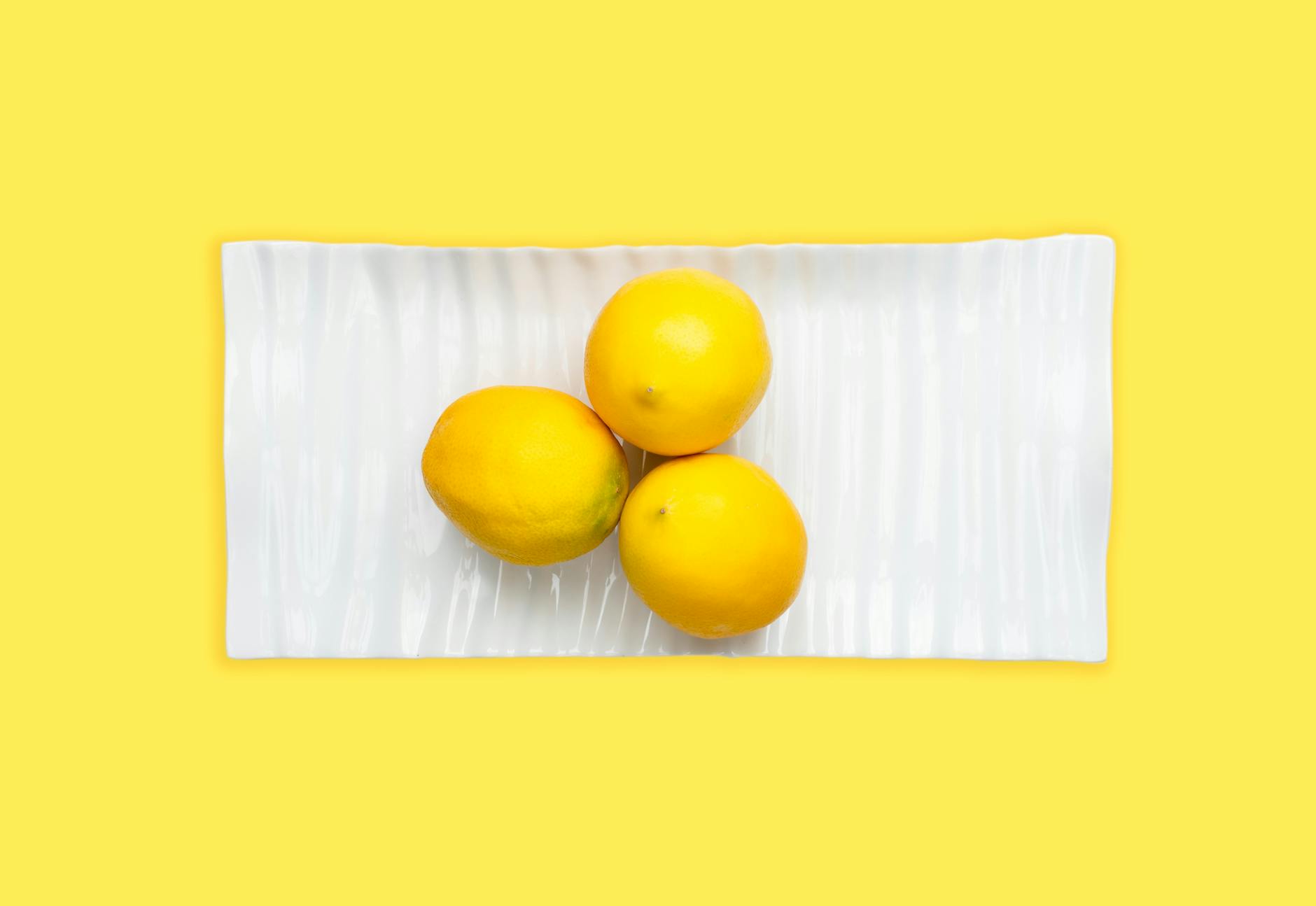 Fresh lemons on white plate with yellow background, symbolizing the Lemon vibrator experience