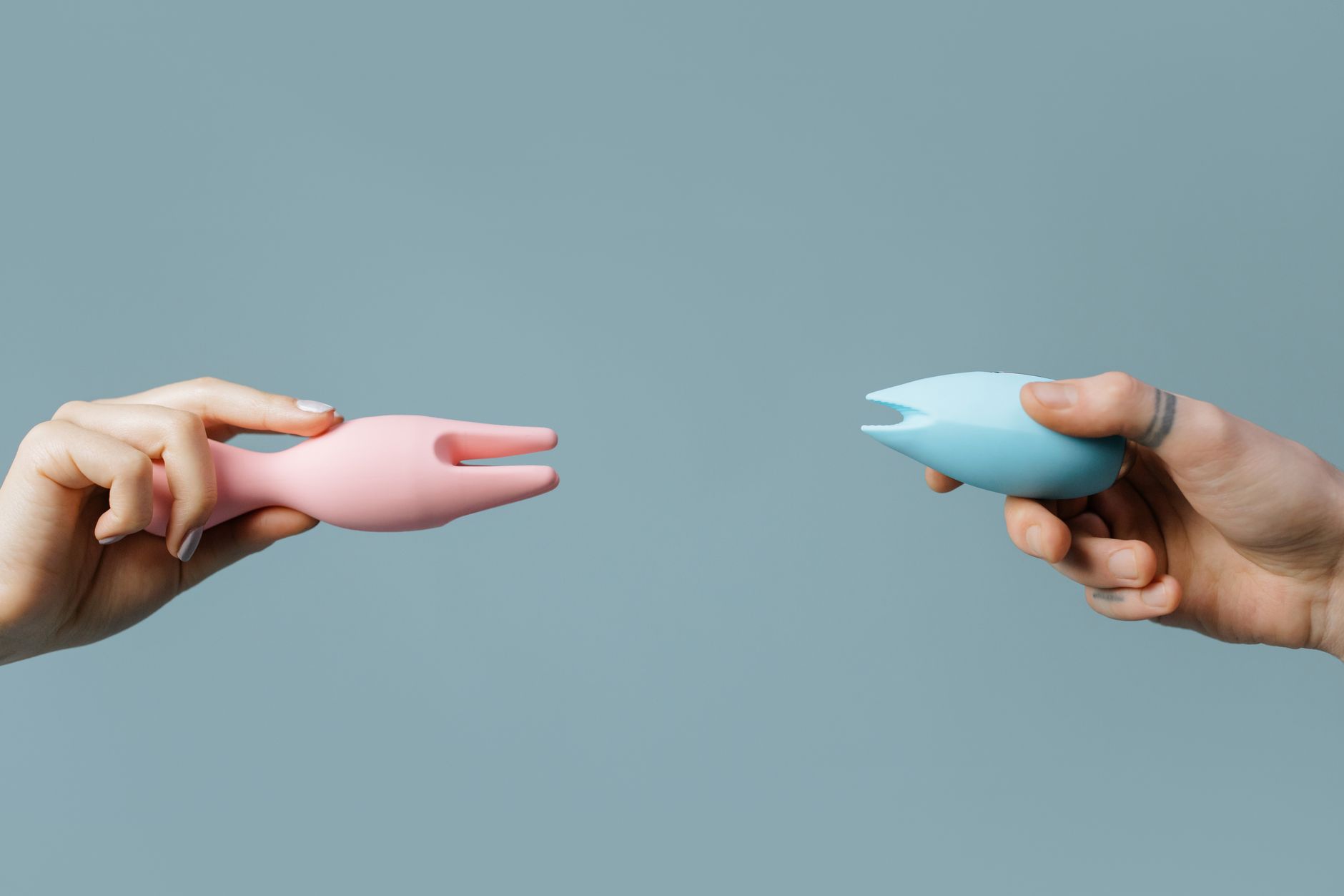 Intimate close-up of hands holding a sleek blue vibrator against a purple background