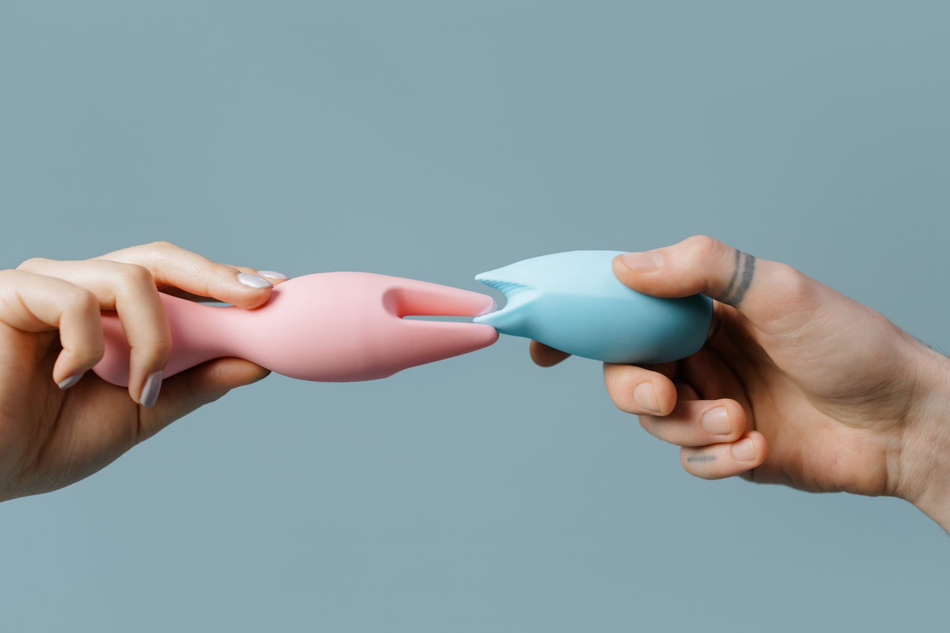 Hands holding pastel-colored silicone toys on a soft background