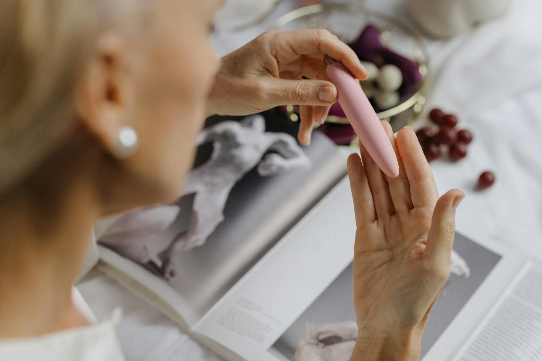 Woman holding blue and pink clitoral vibrators, contemplating renewed sensation and pleasure