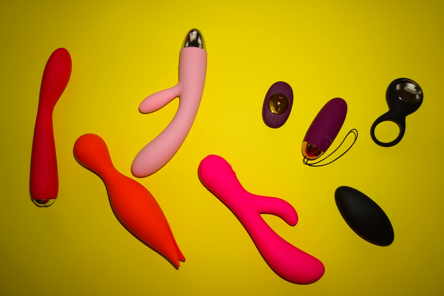 Hand holding a sleek blue clitoral vibrator against a purple background