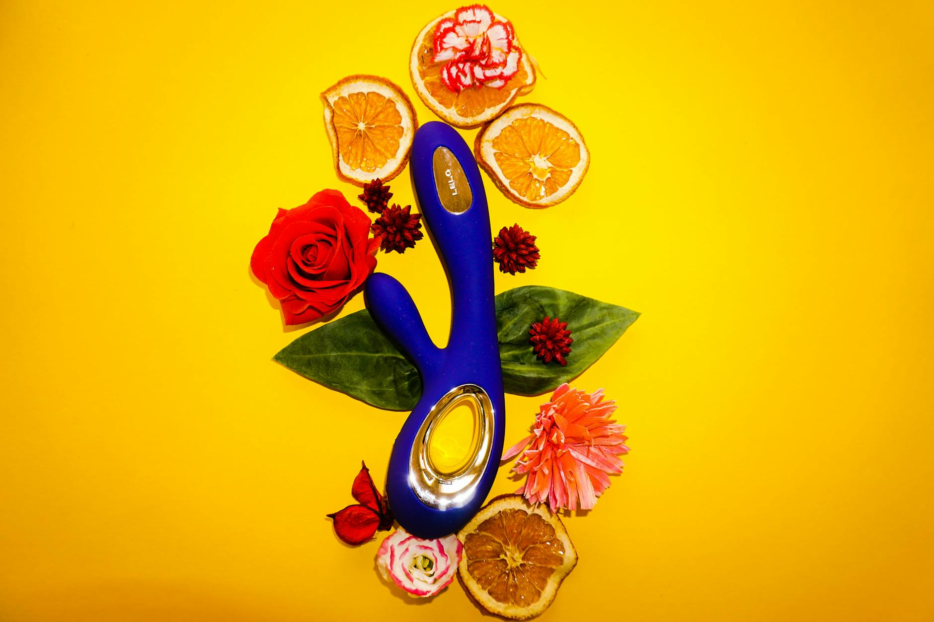 Blue lemon vibrator surrounded by fresh lemons and citrus slices on a bright yellow background
